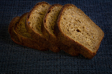 Cut slices of dark bread on the black background