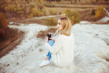 Pensive lonely girl sitting in the mountains with a cup of coffee, autumn time
