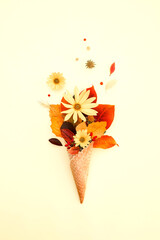 Autumn bouquet of yellow leaves and flowers in ice cream cone, creative autumn concept