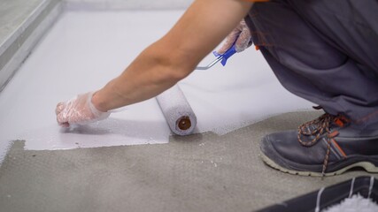 Contract painter painting garage floor to speed up selling of home. Paint the floor with a roller.