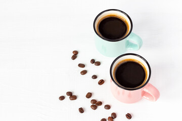 Obraz na płótnie Canvas Pink and azure cups of fresh coffee with grains on white wooden background. Copy space