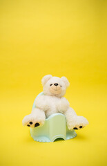 white Teddy bear on a pot on a yellow background. Vertical orientation