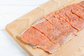 Raw fillet pink salmon with salt and pepper on wooden board. Cooking red fish