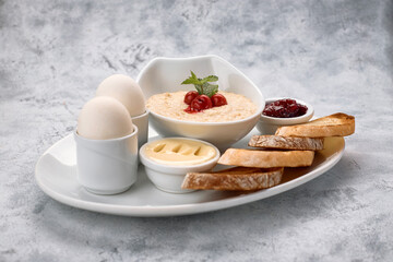 Breakfast of porridge, butter, boiled eggs, jam and toast, croutons, on a white background