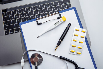 Medical pills,thermometer and stethoscope on the medical claim form close-up.