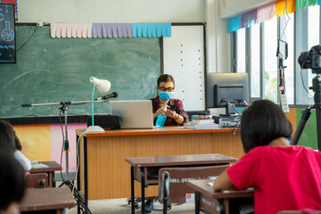 Teacher wearing protective mask to Protect Against Covid-19 with elementary student  in classroom online after covid-19 quarantine and lockdown,New normal lifestyle during corona virus.