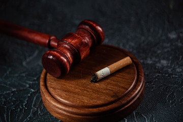 Judge gavel and broken cigarette on grey table. Tobacco law.