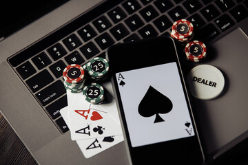 Stack of сhips, smartphone and playing cards on keaboard. Top view. Online casino concept.