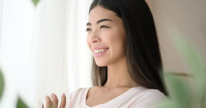 Happy korean woman looking out through window