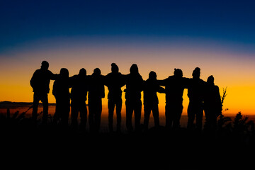 silhouettes of people together in a beautiful sunset at the mountain