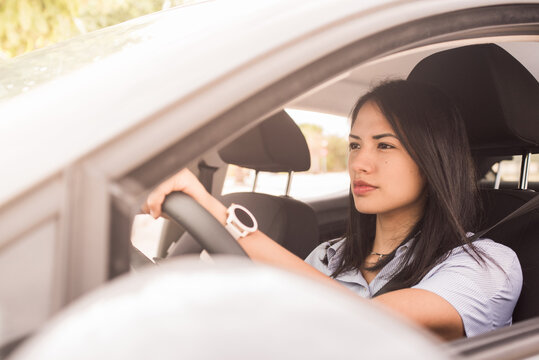 Young latin girl driving a car view through open side window.