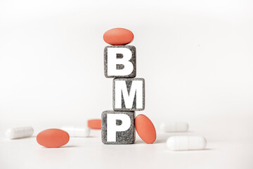 a group of white and red pills and cubes with the word BMP: Basic metabolic panel on them, white background. Concept carehealth, treatment, therapy.