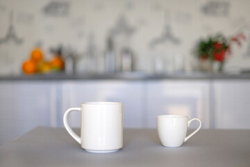Two white cups of coffee on white kitchen defocused background