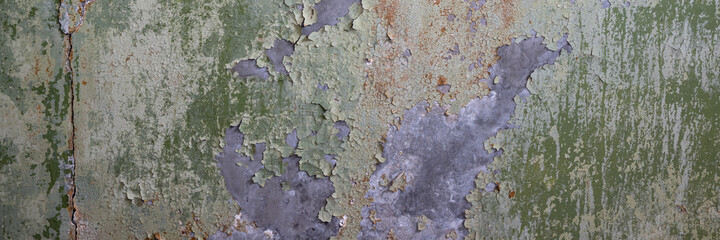 Peeling paint on the wall. Panorama of a concrete wall with old cracked flaking paint. Weathered rough painted surface with patterns of cracks and peeling. Grunge texture for wide panoramic background