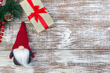 Christmas composition with pine branch, gift box and gnome or swedish tomte, on wooden background,...