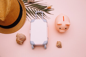 Travel luggage suitcase with piggy bank on pink table with accessories close-up.