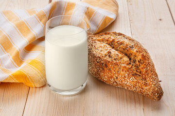 Baked grain bread with flax seeds with glass of milk on wooden table. Breakfast food concept. Close up view