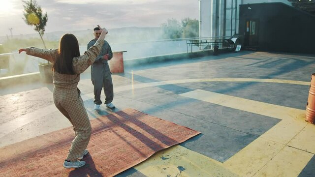 Dance battle. Competition. Skilled handsome urban guy breakdancing and performing hip hop stunts doing crazy movements. Cool girl waiting in background. Activities. Artists.