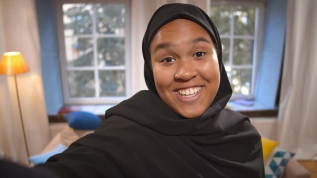 Young muslim woman in hijab talking on video call or filming for internet blog