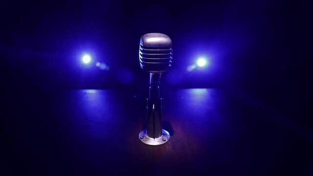 Retro style microphone on background with backlight. Vintage silver Microphone for sound, music, karaoke. Speech broadcast equipment. Live pop, rock musical performance. Selective focus
