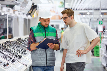 customer want new stove for home, he gets consultation by confident warehouse worker in store