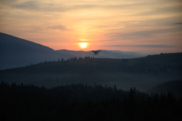 Silhouette Drone flying on mountain sunrise sky with cloud, Aerial photography. mountains landscape with sun and alpine pines. Sunrise
