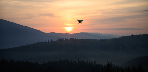 Silhouette Drone flying on mountain sunrise sky with cloud, Aerial photography. mountains landscape with sun and alpine pines. Sunrise
