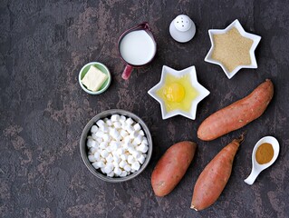 Ingredients for cooking sweet potato casseroles with marshmallows, a traditional Thanksgiving dessert on brown concrete background. American cuisine. Sweet potato recipes.