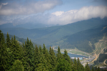 Carpathian mountains summer landscape with sun and alpine pines. Sunny sky with clouds