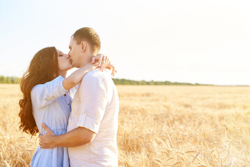 Young couple hugs in the wheat field, kiss and enjoy life. The concept of love and correct non-abusive relationships