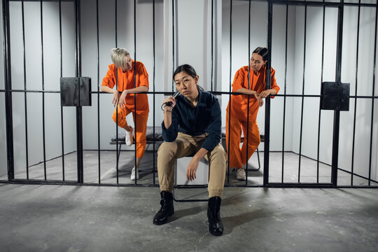 Asian women's prison. In the cell there are two young girls convicted of a criminal offense and a female warden in a guard's uniform
