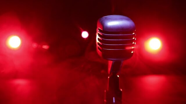 Retro style microphone on background with backlight. Vintage silver Microphone for sound, music, karaoke. Speech broadcast equipment. Live pop, rock musical performance. Selective focus