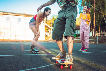 Obraz premium Teen boy on skate with two girls behind him cheering and laughing