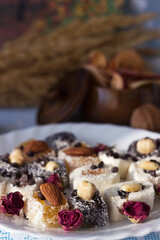Assorted Turkish delight on a white plate. Traditional yellow, white and black sweets with nuts. Goodies