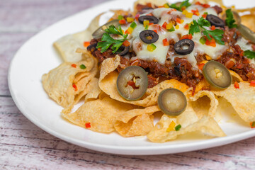 Mexican Famous Food Spicy Ground Beef Nachos. Heated crunchy tortilla chips with melted cheese and jalapeno served a snack food.