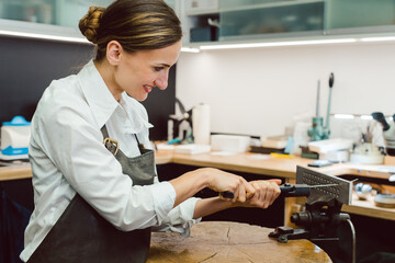 Jewelry designer woman in her workshop pulling wire