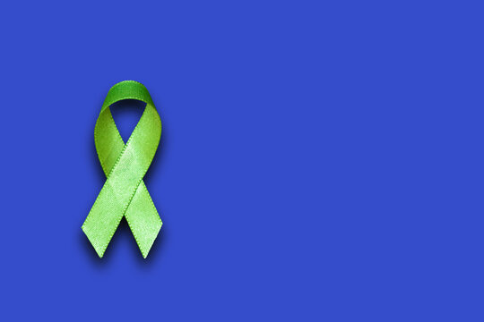 World mental health day concept. Green awareness ribbon and brain symbol on a blue background