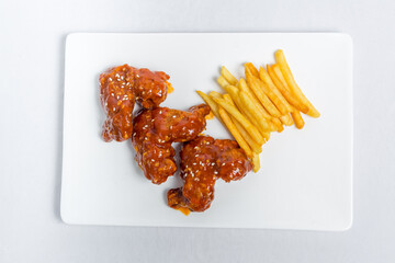 Spicy hot buffalo wings and french fries with white sauce on white plate isolated white background. Top views.