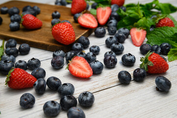 blueberries and strawberries on white background with mint sprigs