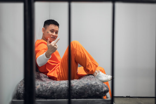 A crazy member of a Chinese mafia gang sits in a cell and shows an obscene gesture to the camera