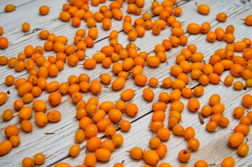 A scattering of sea buckthorn berries on a wooden table. diagonal tree pattern