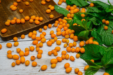 sea buckthorn on a white wooden table with mint sprigs