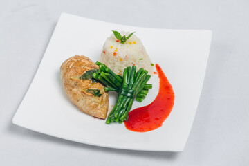 Pan roasted chicken breast with long green beans and light vegetable rice platter. Food decorating with red sauce on a white plate. Isolated white background.