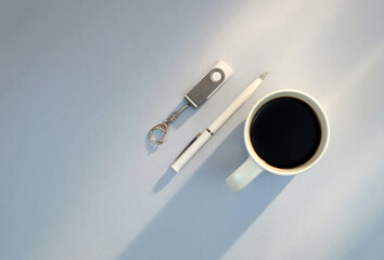 Flash drive, pen, cup of coffee on blue background with copy space, minimalism business style, top view