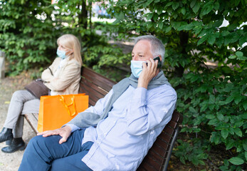 Fototapeta premium Social distancing and separation concept, coronavirus prevention while sitting on a bench in a park
