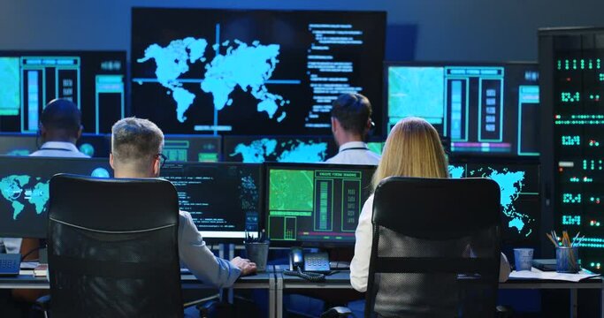 Rear of Caucasian male and female co-workers of digital analytic military center working at computers. Back view on man and woman, colleagues checking information in governmental anti-terrorism office