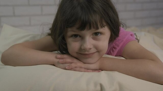 Portrait of a beautiful little girl in bed. A cute little girl lies on the pillow in the morning.