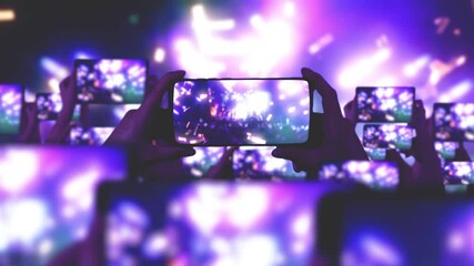 The crowd watches a concert, sings, jumps. Gold confetti. Fans are recording videos on smartphones. A lot of smartphones. Live Stream. Stories. Happy people are watching an amazing concert