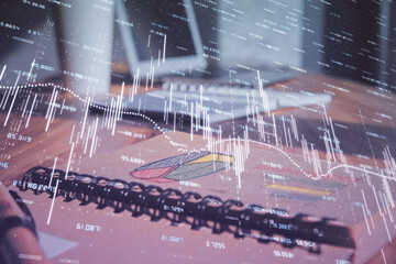 Double exposure of financial graph drawings and desk with open notebook background. Concept of forex market