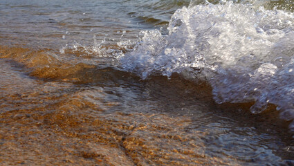 Small waves breaking on the beach in bright sunshine